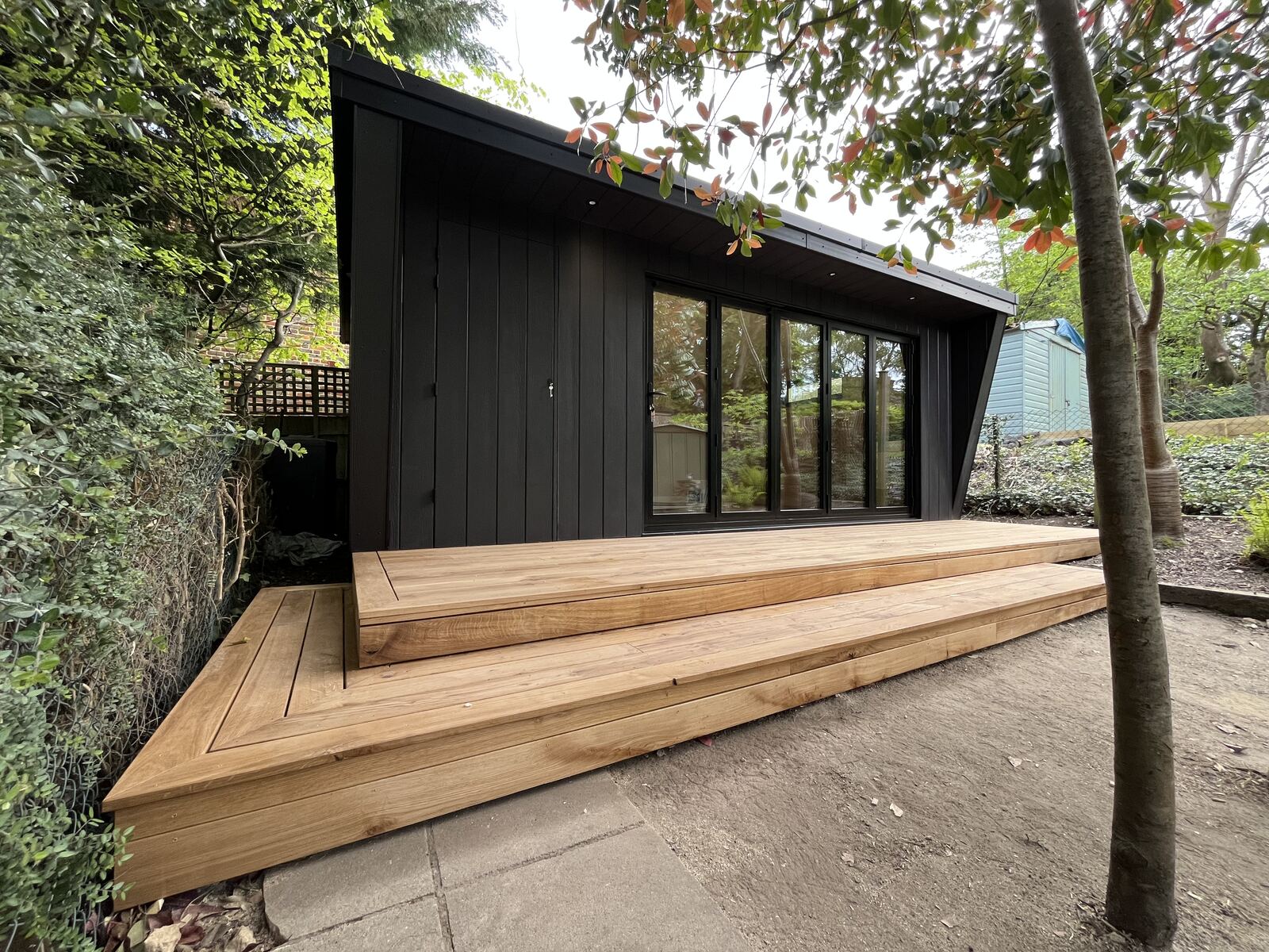 Black-clad garden room with full-width aluminium bi-fold doors, built by Neighbourhood Glazing & Carpentry
